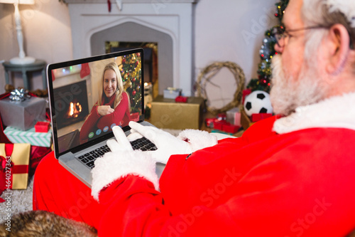 Caucasian santa claus on christmas laptop video call with caucasian woman