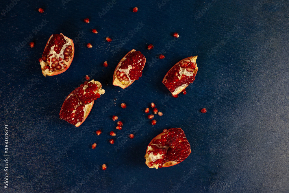 Ripe red pomegranate broken into pieces on blue wooden background