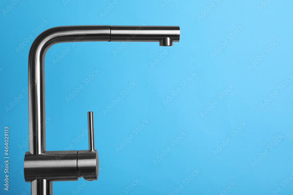 Modern pull out kitchen faucet on light blue background. Space for text