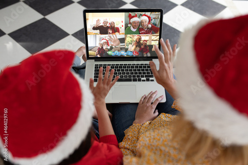 African american mother and child in santa hat on christmas video call on laptop with family