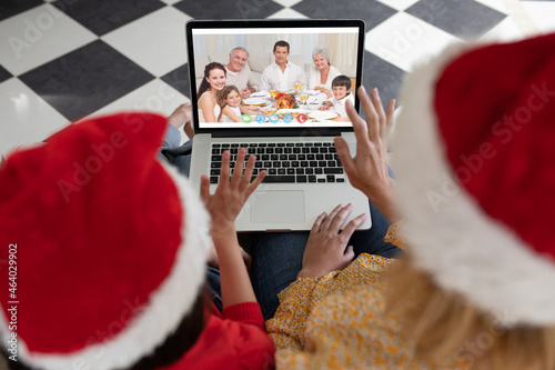 Caucasian mother and child in santa hat on christmas video call on laptop with family