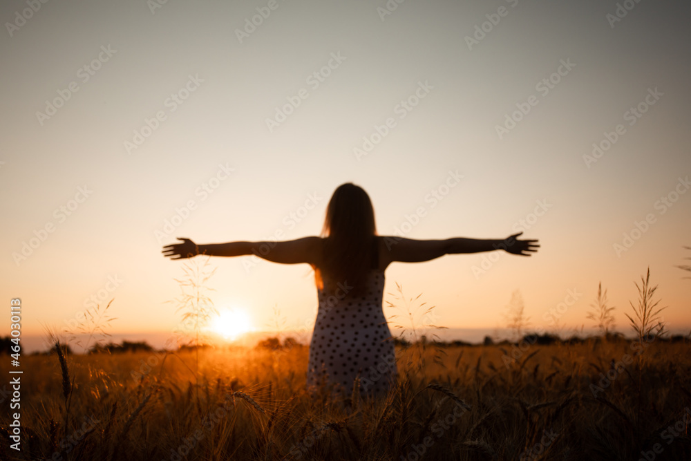 Peaceful woman wellcoming the rising sun in field