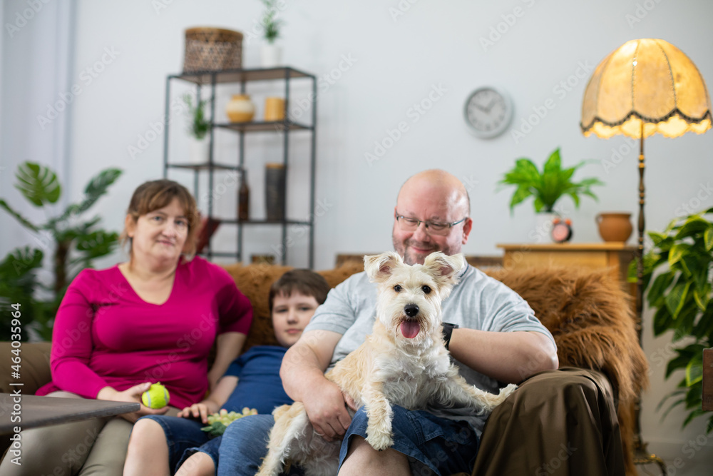 The dog sits on the lap of the head of the family and stares intently into the camera. The dog sits on the lap of the head of the family and stares intently into the camera.