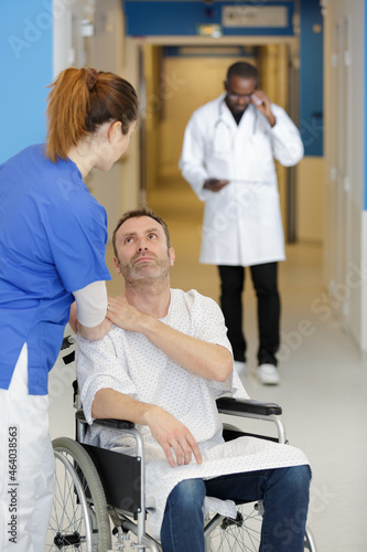 sick man in wheelchair being assisted by female nurse