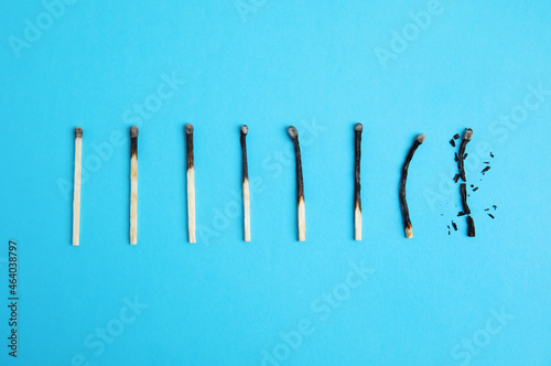 Different stages of burnt matches on light blue background  flat lay