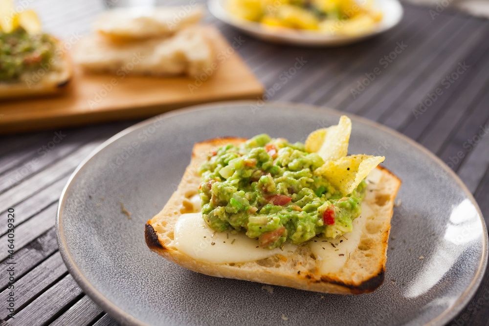 toasted slices of square bread with warm cheese and homemade guacamole on plate for healthy breakfast