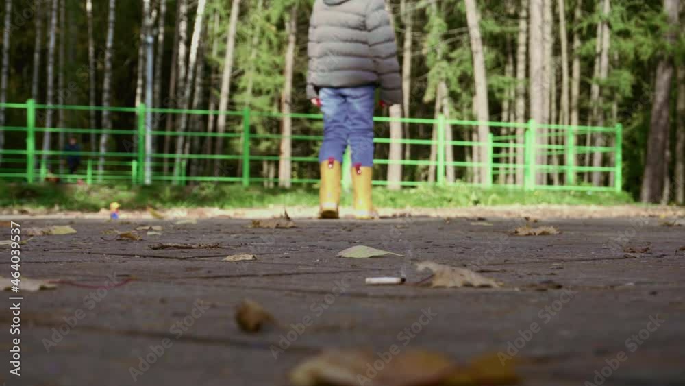 A girl child plays in nature near the children's skateboard playground. Nearby lies a smoking cigarette butt. The concept of child protection and the environment A girl child plays in nature near the children's skateboard playground. Nearby lies a smoking cigarette butt. The concept of child protection and the environment