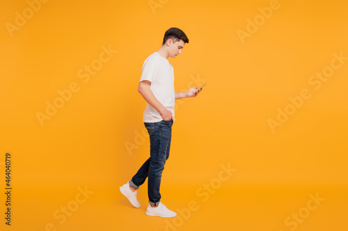 Profile portrait of charming nice attractive guy hold phone browse social network step on yellow background