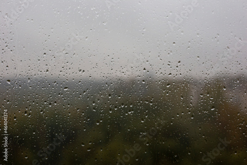 Window with raindrops and blurry view of the autumn forest