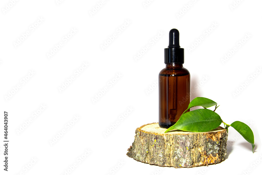 One glass bottle of brown serum with a dropper on a moss-covered wooden podium. Spa cosmetic concept. Place for your text. Organic cosmetics.