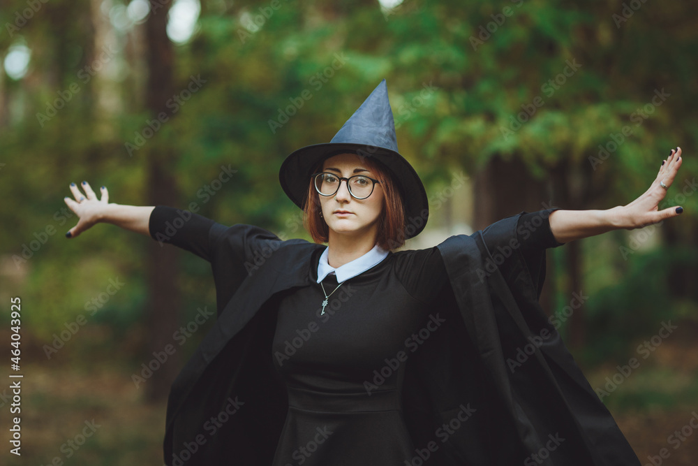 Halloween Witch. Portrait of a girl in a hat and a witch costume in the forest. Ready for trick or treat holiday