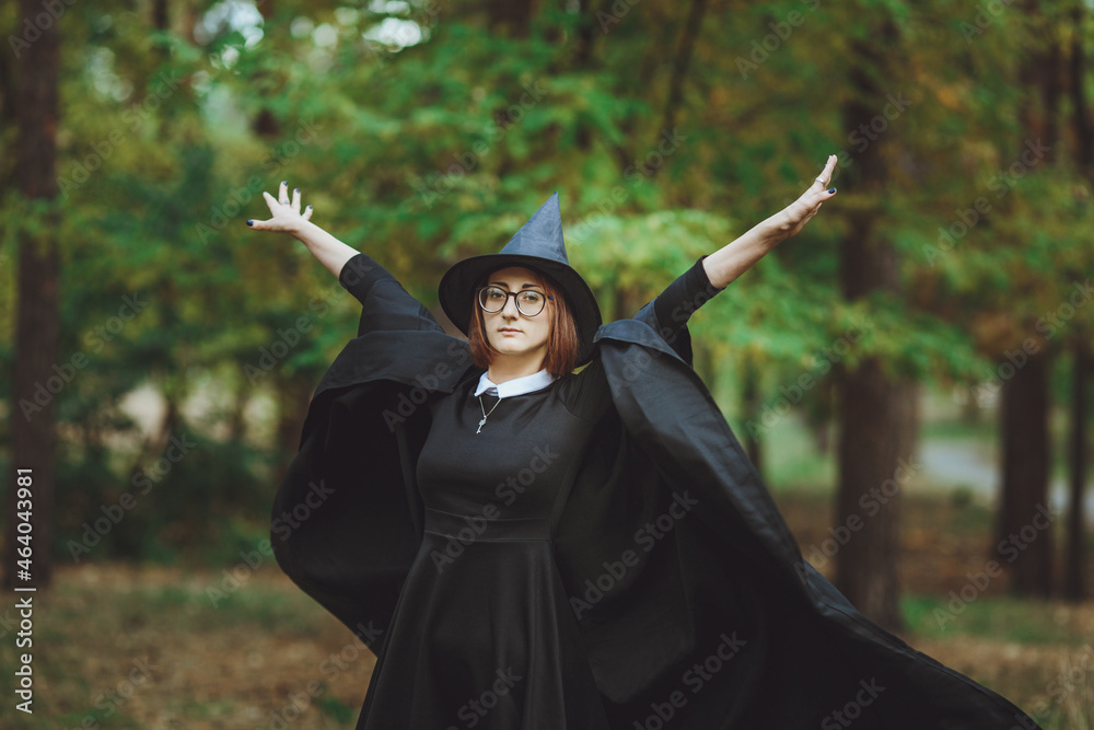 Halloween Witch. Portrait of a girl in a hat and a witch costume in the forest. Ready for trick or treat holiday