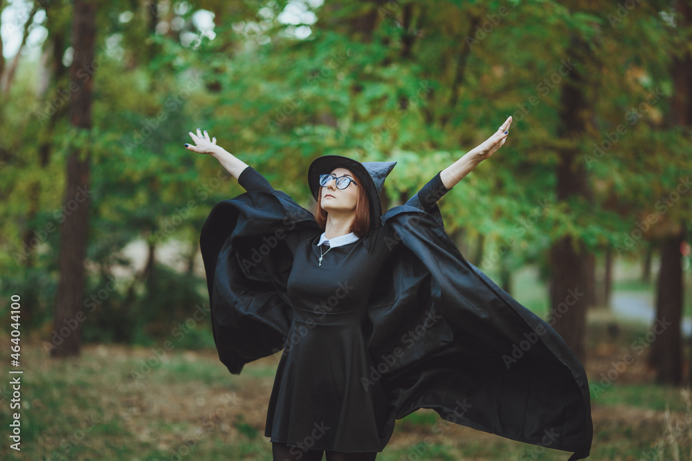 Halloween Witch. Portrait of a girl in a hat and a witch costume in the forest. Ready for trick or treat holiday