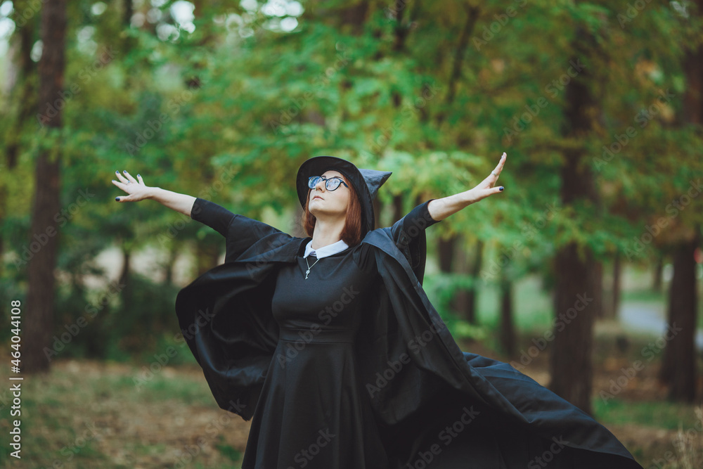 Halloween Witch. Portrait of a girl in a hat and a witch costume in the forest. Ready for trick or treat holiday