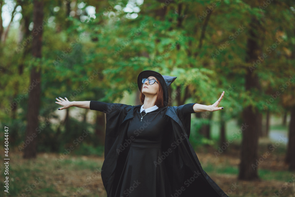 Halloween Witch. Portrait of a girl in a hat and a witch costume in the forest. Ready for trick or treat holiday