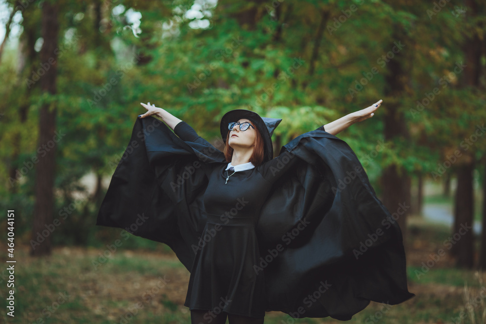 Halloween Witch. Portrait of a girl in a hat and a witch costume in the forest. Ready for trick or treat holiday