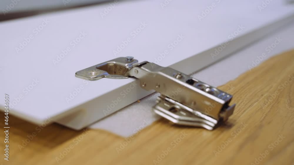 Carpenter man screws hinge to furniture door using electric screwdriver, hands closeup, side view. Carpenter is working making furniture in workshop. Carpenter man screws hinge to furniture door using electric screwdriver, hands closeup, side view. Carpenter is working making furniture in workshop.