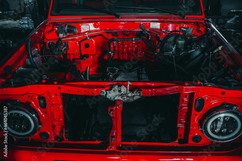 Photo of the open hood of a red car in the garage