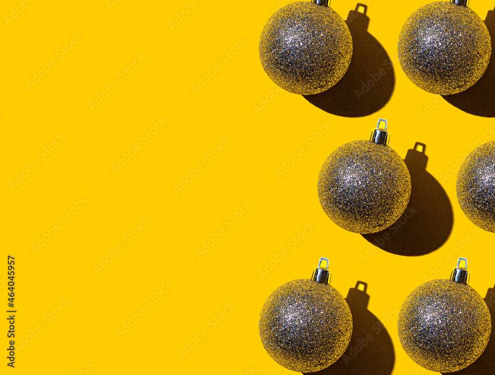 On a bright yellow background, Christmas golden balls with copy space. Christmas and New Year holiday background
