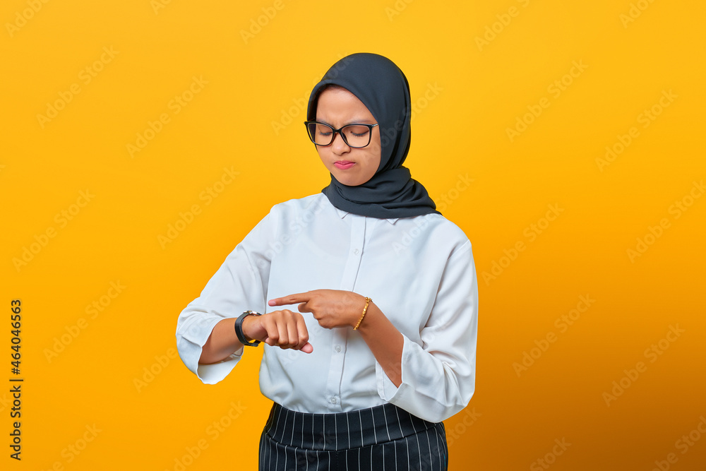 Portrait of young Asian woman checking time on watch isolated over yellow background Portrait of young Asian woman checking time on watch isolated over yellow background