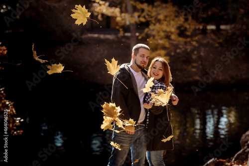 Young people man and woman throw up autumn leaves in autumn in the park during leaf fall