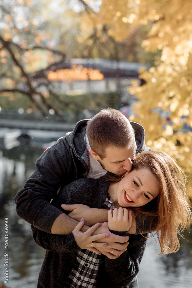 Fototapeta premium Young people man and woman throw up autumn leaves in autumn in the park during leaf fall