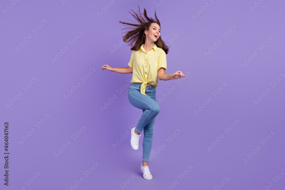 Full length photo of cute millennial brunette lady clubbing wear yellow top jeans sneakers isolated on purple color background