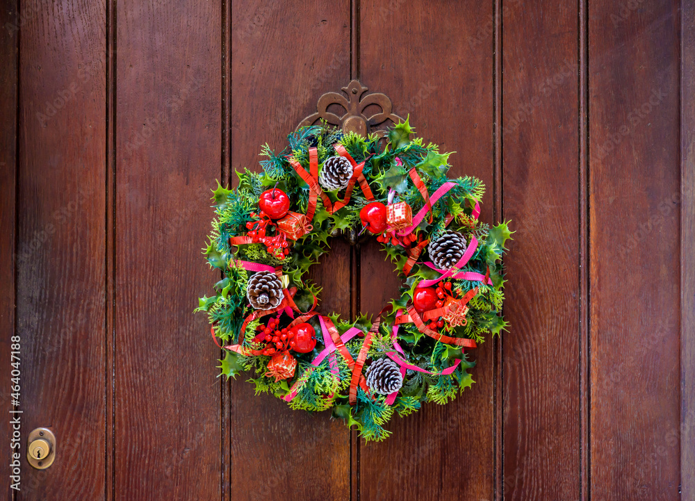 A colorful Christmas crown hanging on an old wooden front door