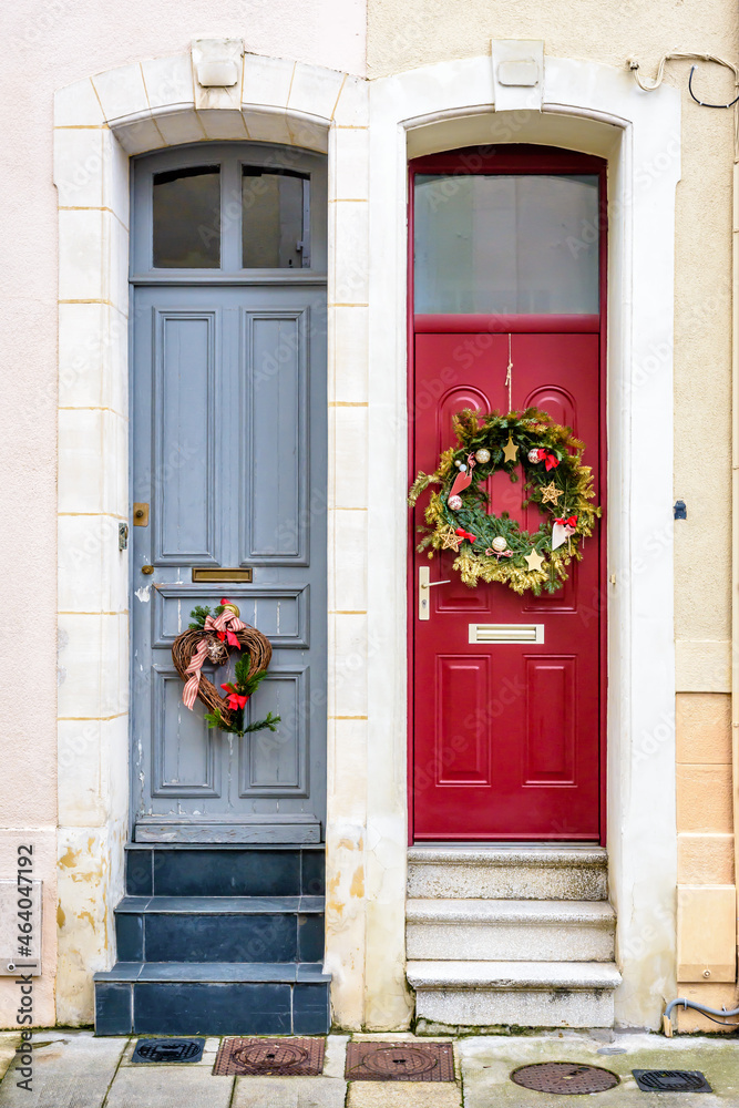 Fototapeta premium Front doors of twin townhouses decorated with Christmas crowns