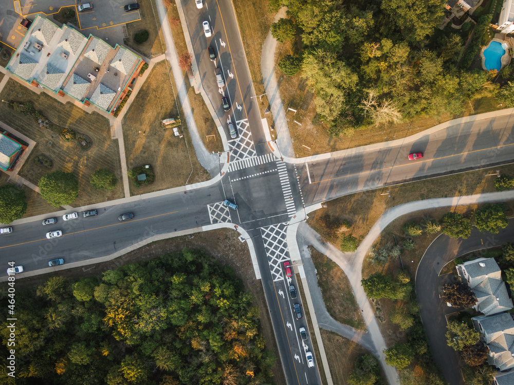 Fototapeta premium Top down aerial view of cars driving through intersection at sunset in a residential neighbourhood in Montreal, Quebec, Canada, North America.