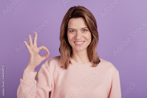 Photo of cute pretty lady demonstrate okey sign beaming smile wear casual shirt on violet background
