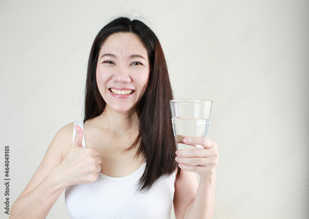 Asian happy smiling beautiful women hold water glass with thumbs up on white background Asian happy smiling beautiful women hold water glass with thumbs up on white background