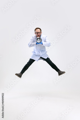 One excited man, chemist, doctor jumping and shouting at megaphone isolated on white background.
