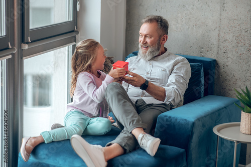 A cute blonde girl giving a gift to her father photo