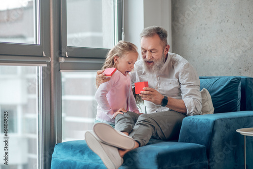 A cute blonde girl giving a gift to her father photo