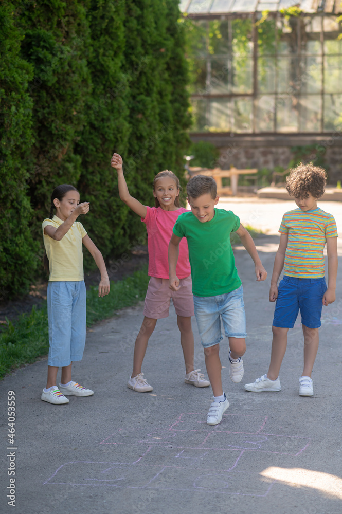 Boy jumping with raised leg and joyful friends Boy jumping with raised leg and joyful friends