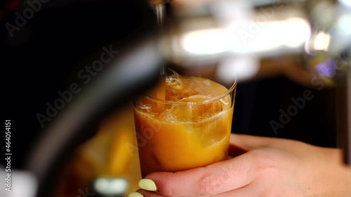 Barista pouring a nitro cold brew coffee into a glass full of ice photo