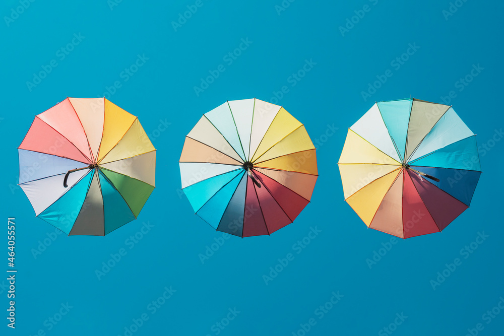 Three multi-coloured sun umbrellas against a blue sky