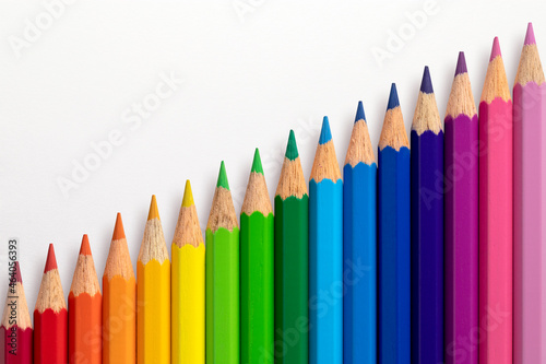 Colour pencils arranged diagonally on a white paper background.
