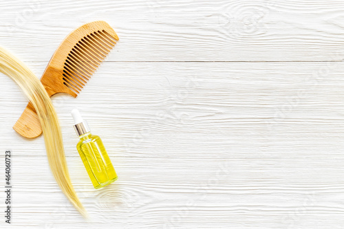 Hair essential oil with wooden comb and blond curl of hair