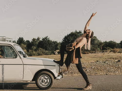 Shirtless hippie showing rock gesture near retro car photo