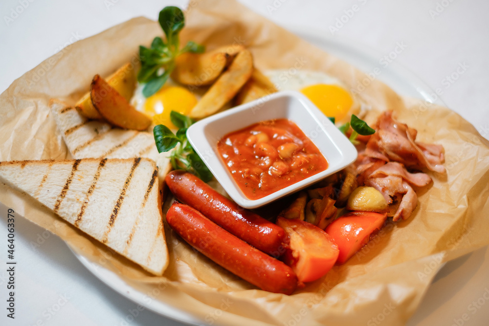 Fried sausages with croutons, bacon and egg. The concept of a delicious hearty homemade breakfast served in a restaurant. Fried sausages with croutons, bacon and egg. The concept of a delicious hearty homemade breakfast served in a restaurant.