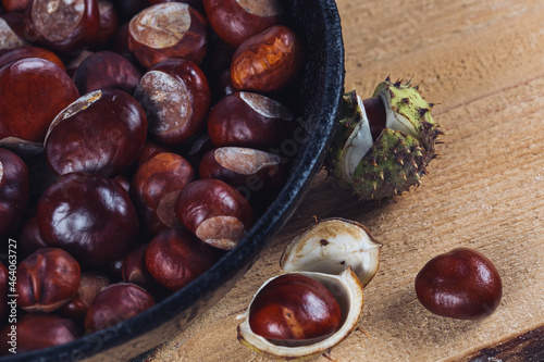 Close up view of chestnuts in a cast iron pan on a wooden background