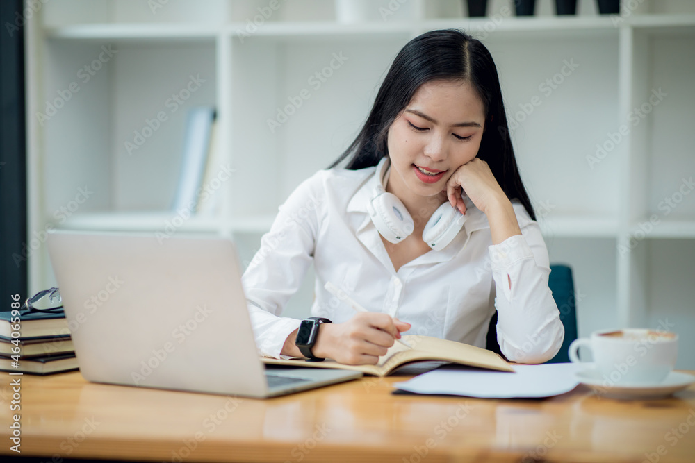 Online Education For Asian Young Women. Student Happy Arabic Girl In Headscarf And Headset Studying With Laptop At Home, Taking Notes While Watching Webinar Online Education For Asian Young Women. Student Happy Arabic Girl In Headscarf And Headset Studying With Laptop At Home, Taking Notes While Watching Webinar