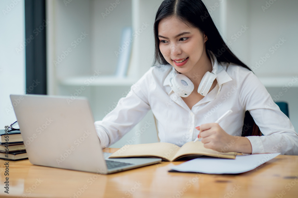 Online Education For Asian Young Women. Student Happy Arabic Girl In Headscarf And Headset Studying With Laptop At Home, Taking Notes While Watching Webinar Online Education For Asian Young Women. Student Happy Arabic Girl In Headscarf And Headset Studying With Laptop At Home, Taking Notes While Watching Webinar