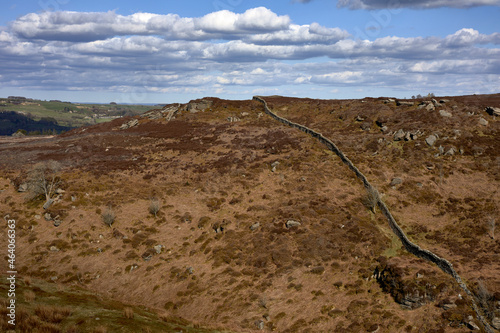 A steep, dry stone wall leads up to a rocky outcrop on high moorland photo