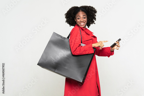 Black woman pointing finger at her cellphone while smiling