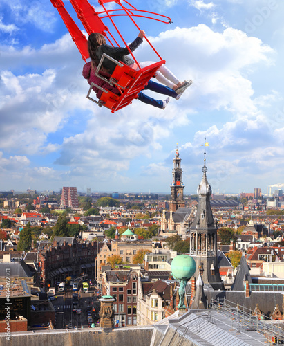 Photography People on red seesaw swinging high in the air space against beautiful blue sky above the town
