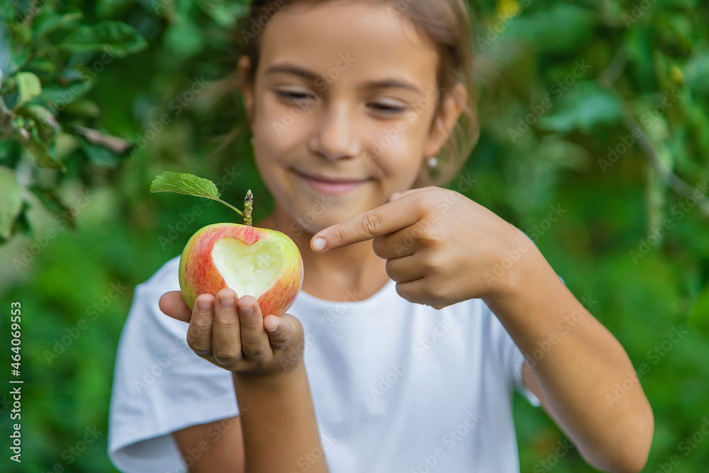 The child eats an apple in the garden. Selective focus. The child eats an apple in the garden. Selective focus.