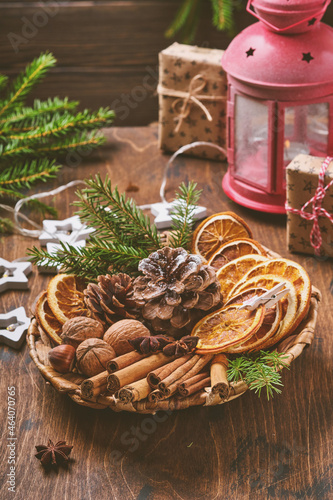 Billede på lærred Dry orange, star anise, cinnamon, pine cones and fir tree in rustic plate on wooden table